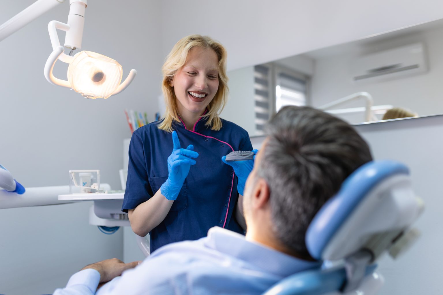 Dentist doctor showing jaw model at dental clinic, dental bonding concept.