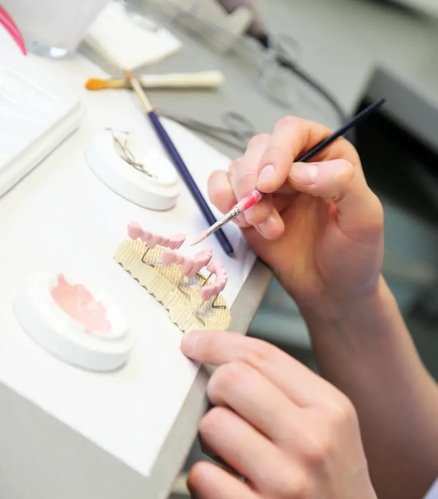 Dental technician applying material to a model of artificial teeth with a brush