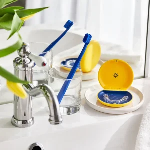 Invisalign clear aligners in a case next to a toothbrush and glass by a bathroom sink