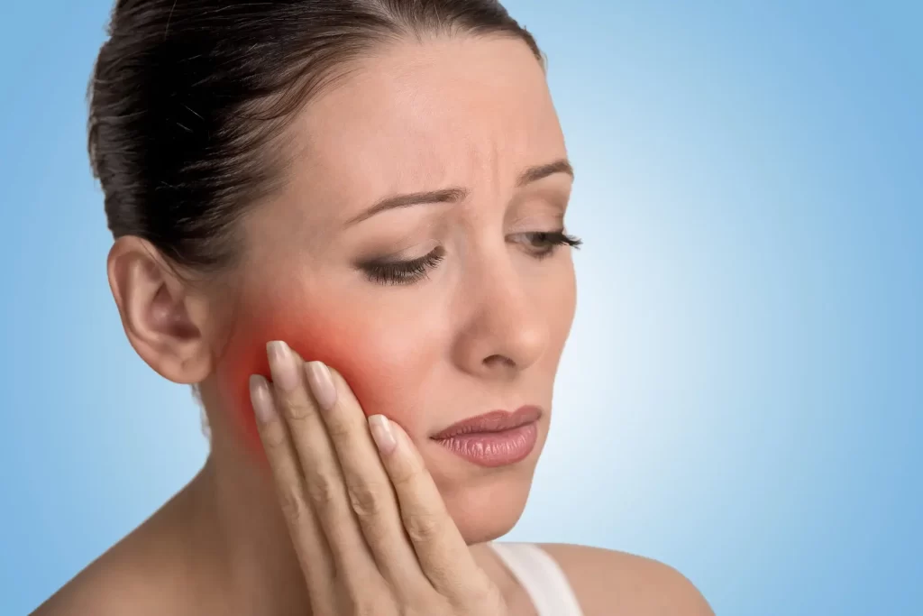 Patient holding their cheek because of a gum abscess
