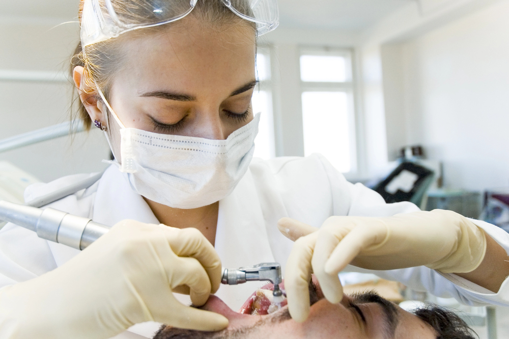 Oral hygienist using a polishing tool while cleaning a patient’s teeth