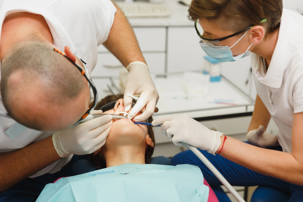 Dental staff cleaning a patient’s teeth during an oral hygienist visit in a bright clinic